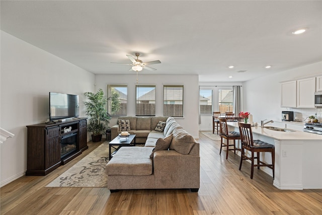 living room with sink, light hardwood / wood-style floors, a healthy amount of sunlight, and ceiling fan