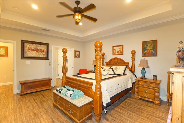 bedroom with crown molding, ceiling fan, a tray ceiling, and hardwood / wood-style floors