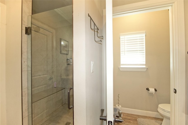 bathroom featuring hardwood / wood-style flooring, walk in shower, and toilet