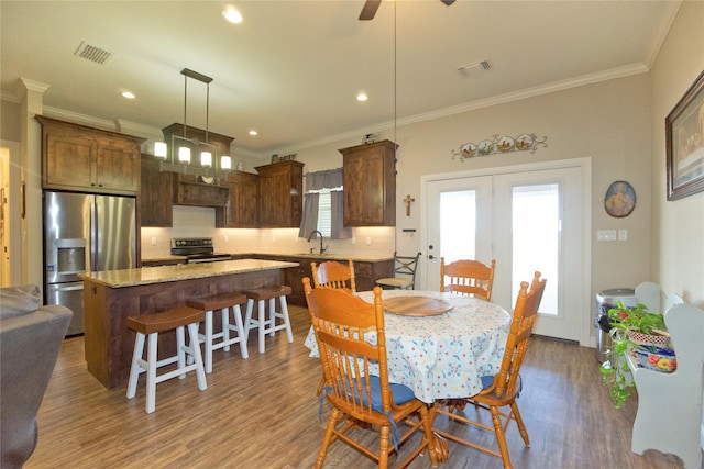 dining room featuring wood-type flooring, sink, and crown molding