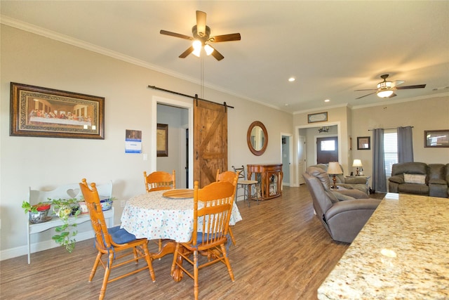 dining room featuring hardwood / wood-style flooring, ornamental molding, a barn door, and ceiling fan