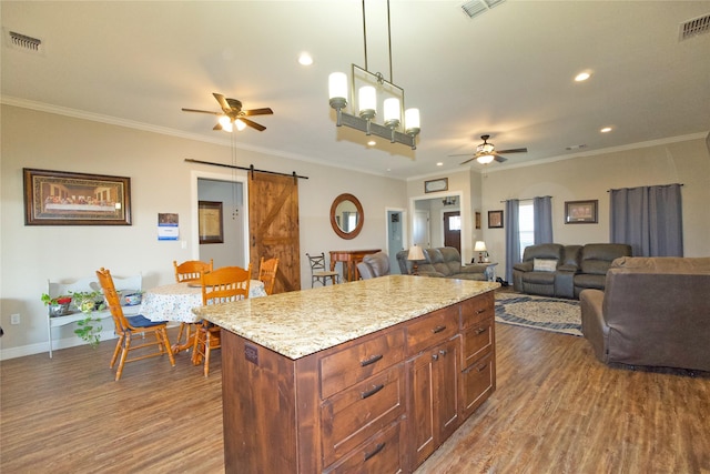 kitchen featuring a kitchen island, wood-type flooring, hanging light fixtures, ceiling fan, and a barn door