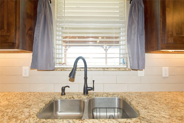 kitchen with light stone countertops, sink, and decorative backsplash