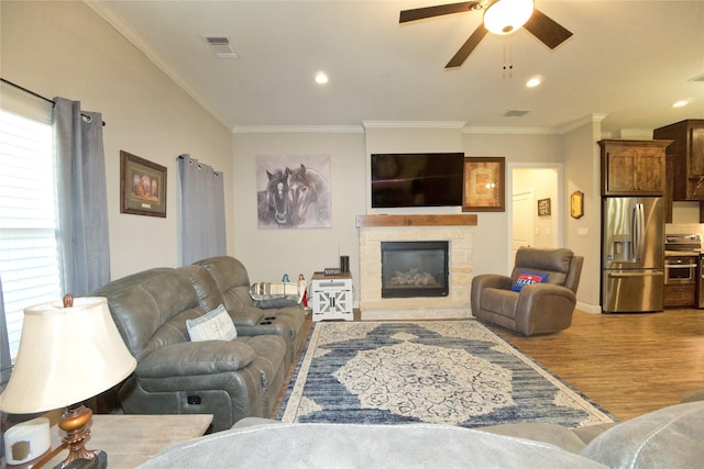 living room featuring a fireplace, ornamental molding, light hardwood / wood-style floors, and ceiling fan