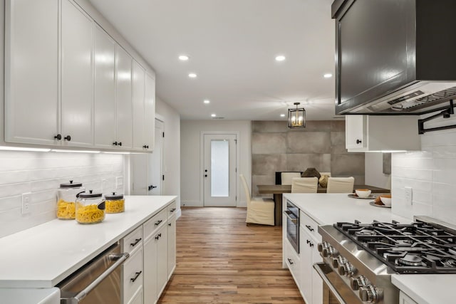 kitchen featuring white cabinetry, stainless steel appliances, light hardwood / wood-style floors, and exhaust hood