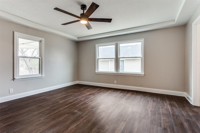 empty room featuring a textured ceiling, dark hardwood / wood-style floors, and a healthy amount of sunlight