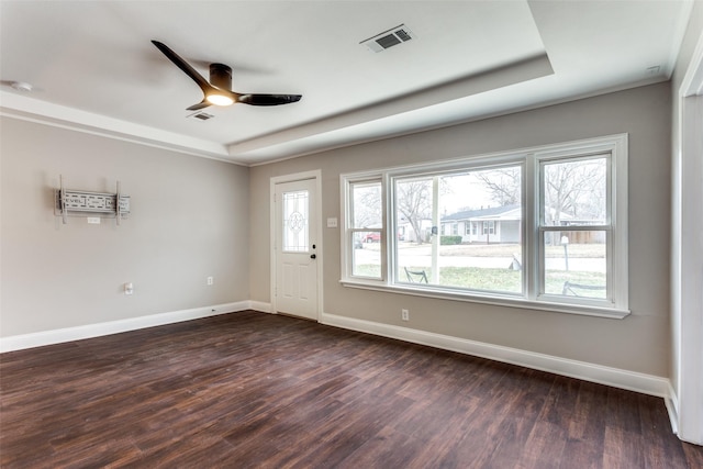 interior space with a raised ceiling, dark hardwood / wood-style floors, and ceiling fan