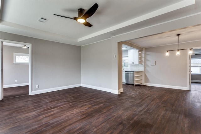 unfurnished living room featuring ceiling fan, ornamental molding, dark hardwood / wood-style flooring, and a tray ceiling