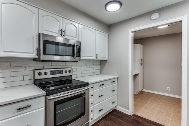 kitchen featuring backsplash, stainless steel appliances, light stone counters, and white cabinets