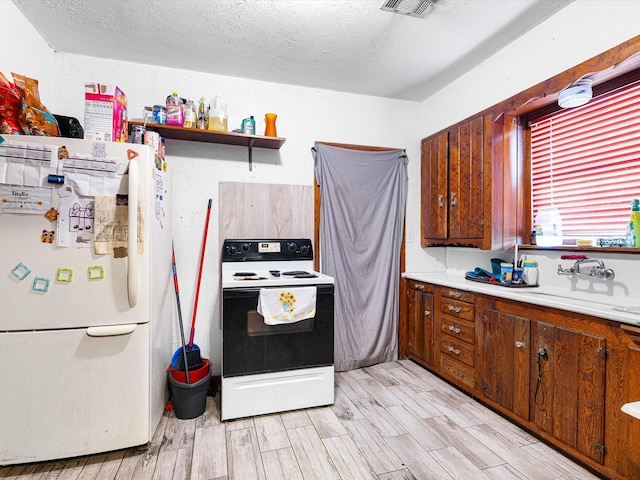 kitchen featuring white refrigerator, sink, light hardwood / wood-style floors, and electric stove