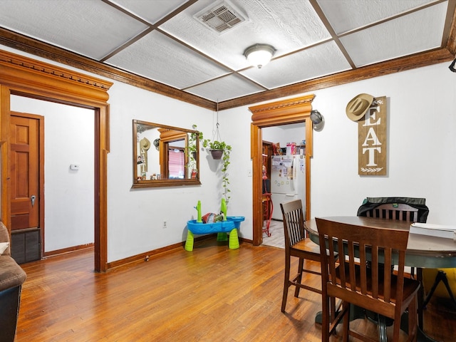 dining area with wood-type flooring and ornamental molding