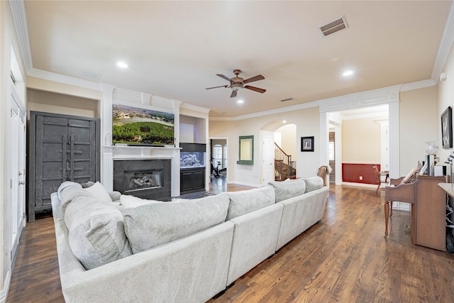 living room featuring crown molding, dark wood-type flooring, and ceiling fan