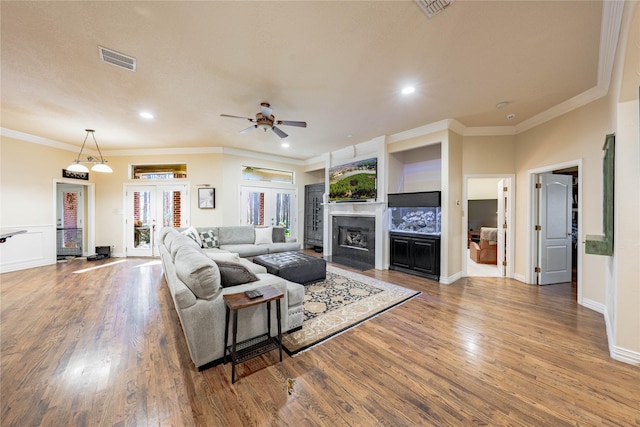 living room with hardwood / wood-style flooring, ornamental molding, and ceiling fan