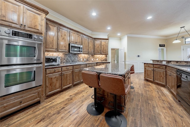 kitchen featuring dark stone countertops, hanging light fixtures, stainless steel appliances, and a center island