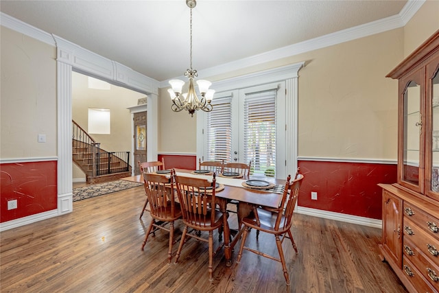 dining space featuring dark wood-type flooring, ornamental molding, and a chandelier