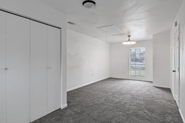 unfurnished bedroom with a textured ceiling and dark colored carpet