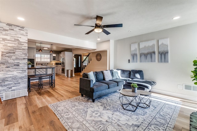 living room featuring ceiling fan and light hardwood / wood-style floors