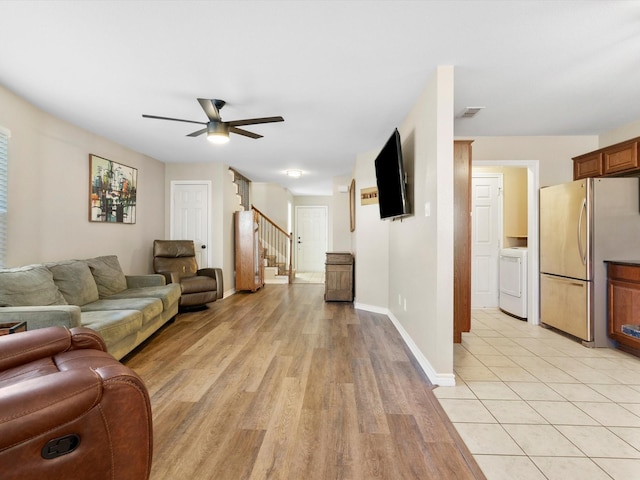 living room featuring ceiling fan, washer / dryer, and light hardwood / wood-style floors