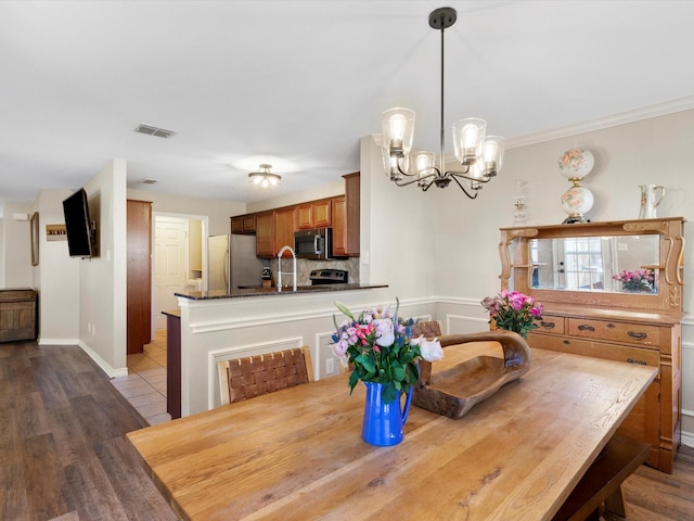 dining area featuring crown molding, light hardwood / wood-style floors, sink, and a notable chandelier