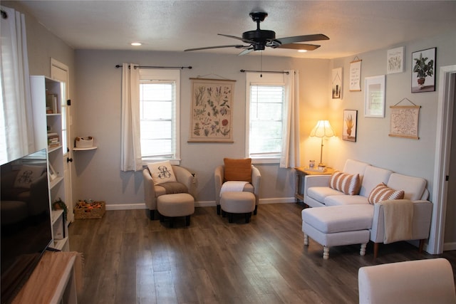 living room featuring dark wood-type flooring, ceiling fan, and a textured ceiling