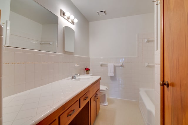 bathroom with tile walls, vanity, a bath, and toilet