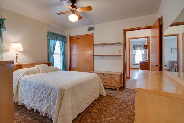 bedroom featuring ceiling fan, dark carpet, and a closet