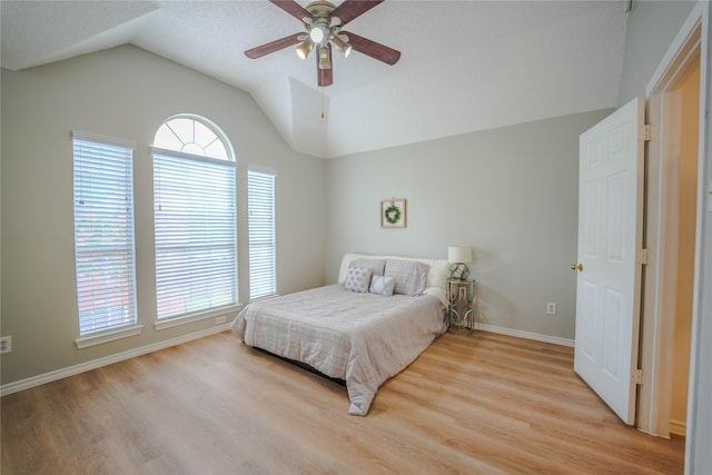 bedroom with multiple windows, vaulted ceiling, ceiling fan, and light hardwood / wood-style flooring