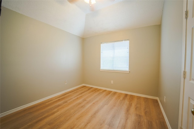 empty room with ceiling fan, vaulted ceiling, and light wood-type flooring