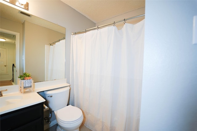 bathroom featuring vanity, a textured ceiling, and toilet