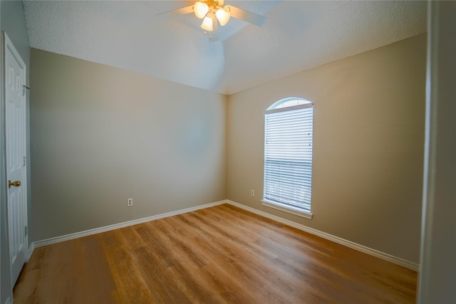 empty room with light hardwood / wood-style flooring, ceiling fan, and vaulted ceiling