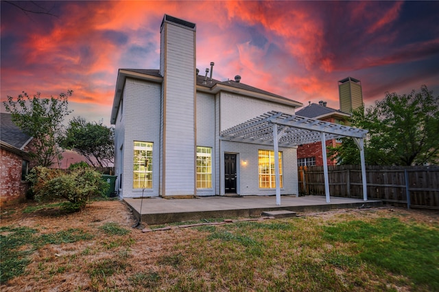 back house at dusk with a yard, a pergola, and a patio