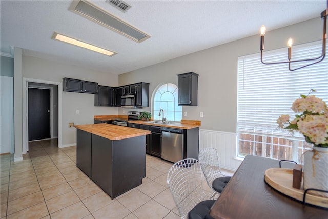 kitchen featuring wooden counters, stainless steel appliances, sink, and light tile patterned floors