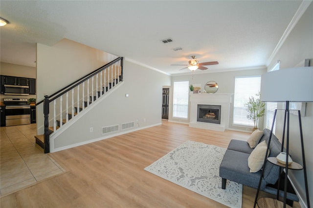 living room with ceiling fan, ornamental molding, and light hardwood / wood-style floors