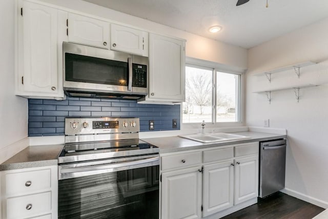 kitchen with stainless steel appliances, open shelves, a sink, and decorative backsplash