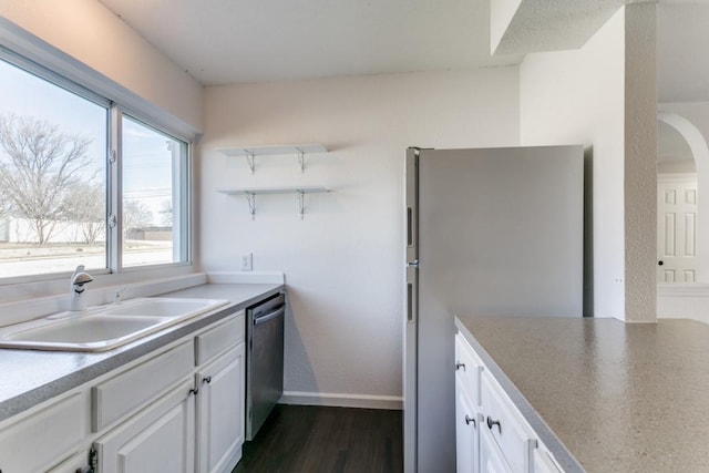 kitchen featuring dark wood-style floors, appliances with stainless steel finishes, a sink, and white cabinets