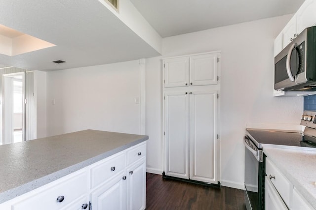 kitchen with baseboards, visible vents, white cabinets, appliances with stainless steel finishes, and dark wood-type flooring