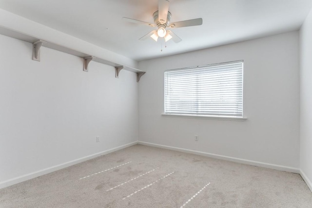 carpeted spare room featuring baseboards and a ceiling fan