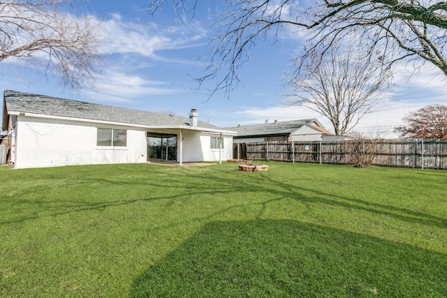 back of property with a fire pit and a lawn