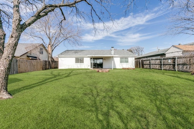 back of house featuring a lawn, a chimney, and a fenced backyard