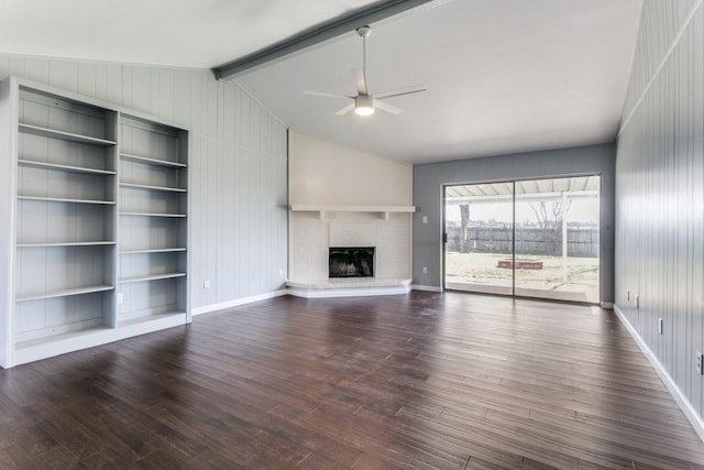 unfurnished living room featuring vaulted ceiling with beams, dark wood-type flooring, a brick fireplace, and a ceiling fan