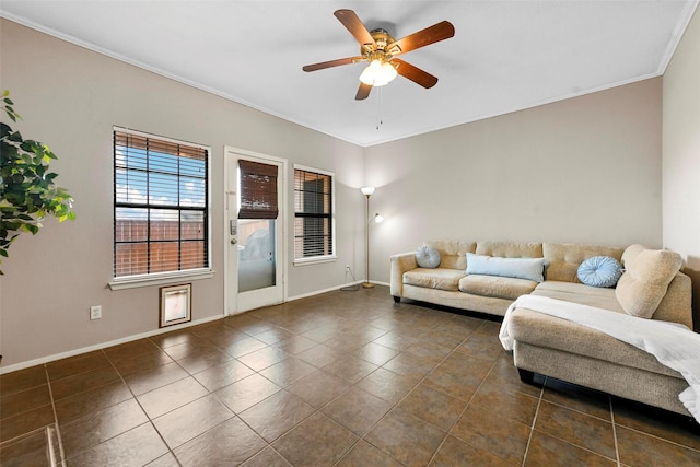 living room with ceiling fan, ornamental molding, and dark tile patterned flooring