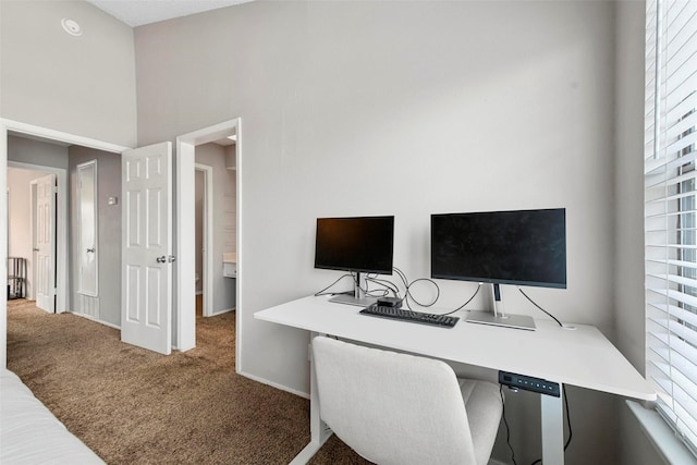 office space featuring a towering ceiling and carpet