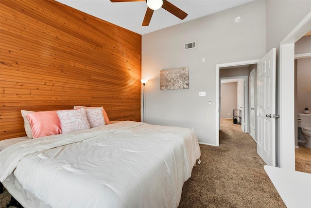 carpeted bedroom with ceiling fan, high vaulted ceiling, and wood walls