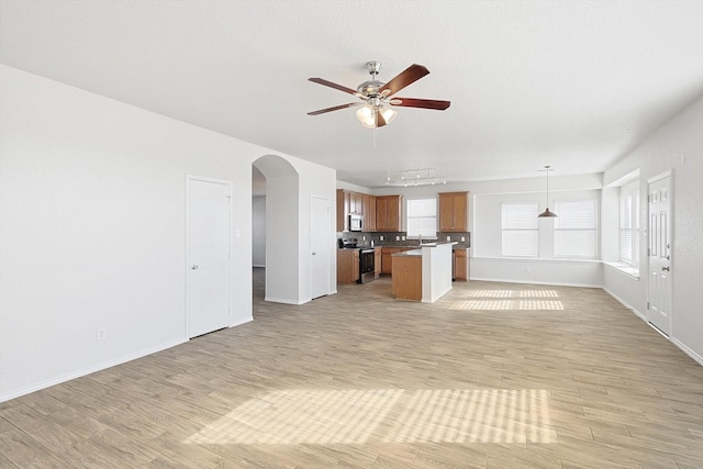 unfurnished living room with sink, ceiling fan, and light wood-type flooring