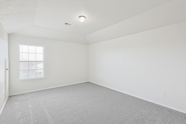 spare room with lofted ceiling, carpet flooring, and a textured ceiling