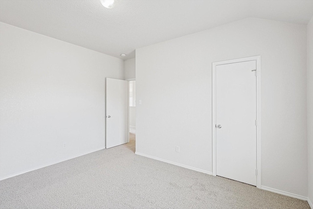 empty room with light carpet and vaulted ceiling