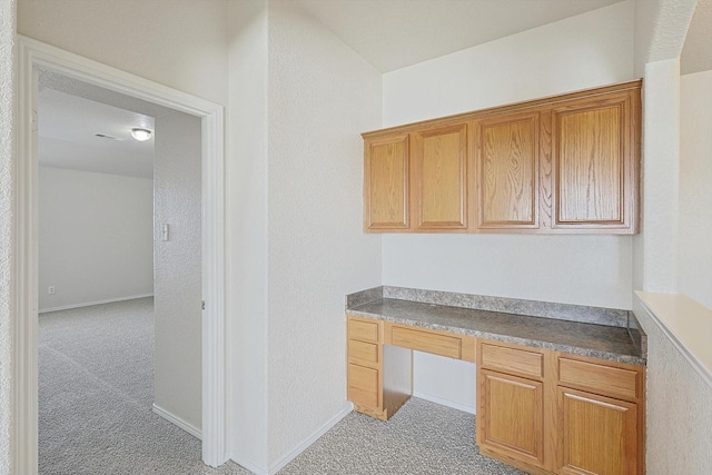 unfurnished office featuring light colored carpet and built in desk