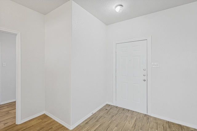 entrance foyer with a textured ceiling and light hardwood / wood-style flooring