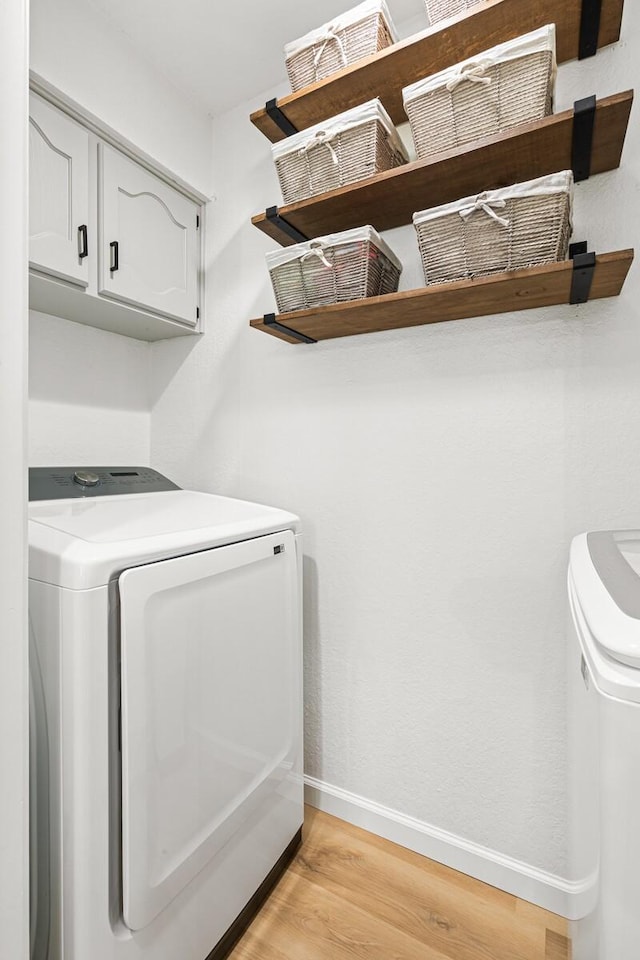 laundry room with cabinets, washing machine and clothes dryer, and light wood-type flooring