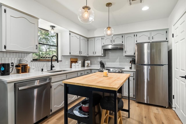 kitchen featuring stainless steel appliances, sink, pendant lighting, and light wood-type flooring